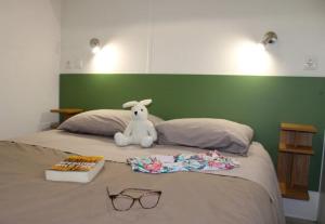 a stuffed rabbit sitting on a bed with a book and glasses at ZEcamping 3 étoiles avec piscine chauffée en pleine nature in Belmont-sur-Rance