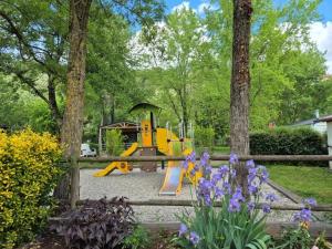a playground in a garden with purple flowers at ZEcamping 3 étoiles avec piscine chauffée en pleine nature in Belmont-sur-Rance +5 photos