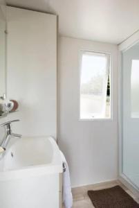 a white bathroom with a sink and a window at ZEcamping 3 étoiles - piscine chauffée haute saison in Antonne-et-Trigonant