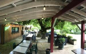 an outdoor patio with tables and chairs and a tree at ZEcamping 3 étoiles - piscine chauffée haute saison in Antonne-et-Trigonant