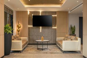 a living room with two couches and a tv at Protea Hotel by Marriott Kinshasa in Kinshasa