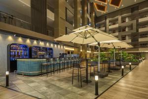 a restaurant with tables and umbrellas in a building at Protea Hotel by Marriott Kinshasa in Kinshasa