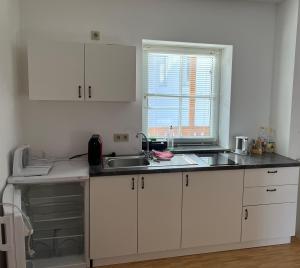 a kitchen with white cabinets and a sink and a window at Gästezimmer Sengstschmid in Windhaag bei Freistadt