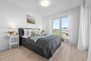 a white bedroom with a bed and a large window at Annas Heimat am Meer in Kappeln