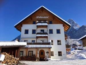 a building in the snow with mountains in the background at Das Wetterstein in Ehrwald