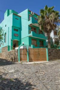 a blue building with a gate and a palm tree at Arla Residential in Mindelo