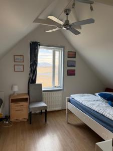 a bedroom with a ceiling fan and a bed and a chair at Laufás Guesthouse in Hellissandur