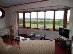 a living room with a large window and a television at Collin Hill House in Castle Douglas