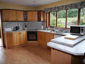 a kitchen with wooden cabinets and a counter top at Collin Hill House in Castle Douglas