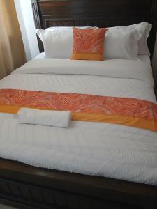 a bed with orange and white sheets and pillows at Machakos Town 3 Bedroom Ensuite in Machakos +7 photos