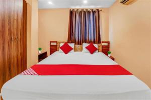 a bedroom with a large white bed with red pillows at Hotel O by OYO PVR in Hyderabad