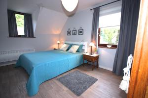 a bedroom with a blue bed and a window at L'O de La Roche in La Roche-en-Ardenne