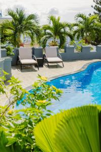 a swimming pool with two chairs and palm trees at The View Boutique Hotel in Vung Tau