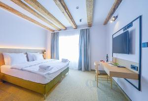 a bedroom with a bed and a desk and a television at Hotel Risnjak in Delnice