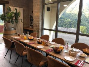 a long table with chairs and a large window at Auberge des isards in Aydius