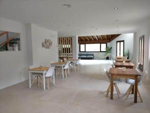 a dining room with wooden tables and white chairs at Casa Kirana - Habitaciones in Bermeo