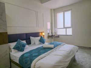 a bedroom with a large bed with blue and white pillows at Hotel Vatsalya by The Holy Meander in Varanasi
