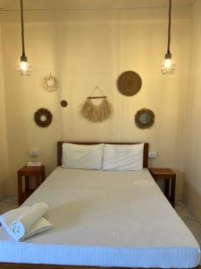a bedroom with a bed with white sheets and baskets on the wall at Azuls Tourist Inn in San Vicente