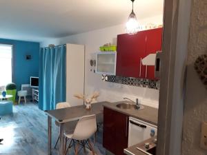 a kitchen with red cabinets and a table with chairs at Au bord des Dunes in Camiers
