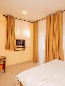 a bedroom with a bed and a window with curtains at River point inn in Arusha