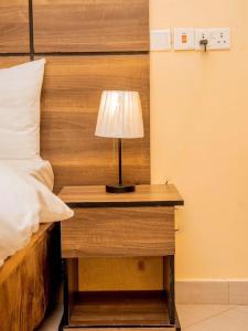 a table with a lamp on it next to a bed at River point inn in Arusha +2 photos