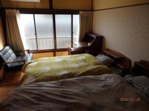 a bedroom with two beds and a window and a chair at Guesthouse ONE WORLD 一棟貸の宿 in Kitsuki