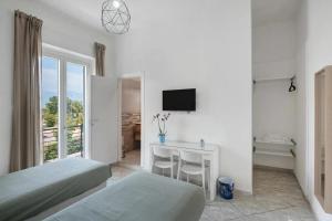 a bedroom with two beds and a desk with a television at GRIMALDI ROOMS Costa d'Amalfi in Pagani