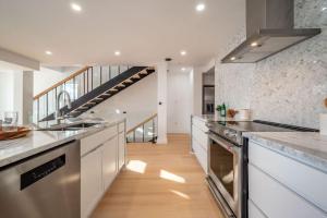 a large kitchen with white counters and a staircase at 4Br 3 Bath Oceanview Modern Home in Halifax +5 photos