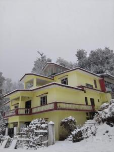 a yellow house with snow in front of it at Mayadeep Resort and Hostels in Chopta
