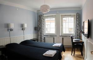 a bedroom with two beds and a desk and windows at Drottning Victorias Örlogshem in Stockholm