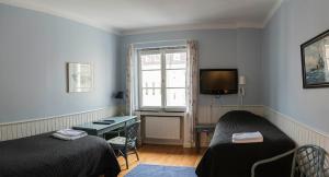 a room with two beds and a tv and a window at Drottning Victorias Örlogshem in Stockholm