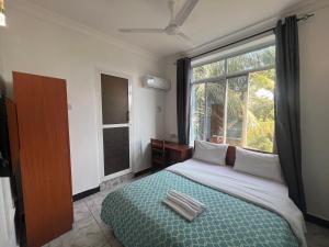 a bedroom with a bed and a large window at PhyllenHotel Tanga in Tanga
