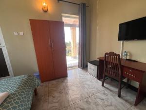 a bedroom with a desk and a bed and a desk with a computer at PhyllenHotel Tanga in Tanga