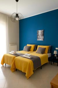 two beds in a room with a blue wall at B&B D'Aponte Home Napoli Est Parcheggio Gratuito in Volla