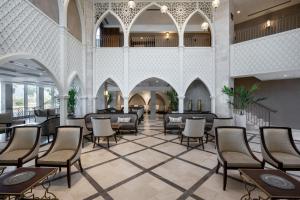 eine Lobby mit Stühlen und Tischen in einem Gebäude in der Unterkunft Palm Beach Hotel - Mehadrin Kosher suitable for Ultra-Orthodox guests in Akkon