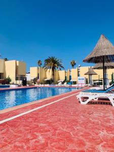 a swimming pool with two lounge chairs and an umbrella at Amazing duplex Las Americas in Costa de Adeje