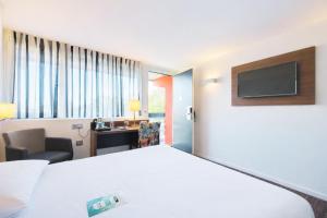 a hotel room with a bed and a tv at Kyriad Bordeaux - Merignac Aéroport in Mérignac