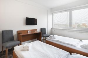 a room with two beds and a desk and a tv at Hotel Veronika in Ostrava