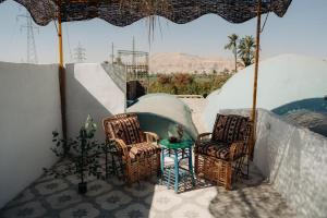 a patio with chairs and a table and a pool at Harmonia House in Al Karnak