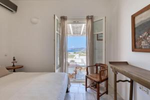 a bedroom with a bed and a desk and a window at Big Blue Sunset View in Angairiá