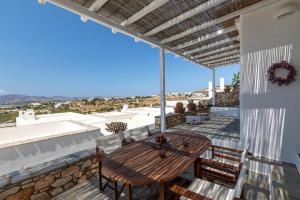 a patio with a wooden table and chairs on a roof at Big Blue Sunset View in Angairiá