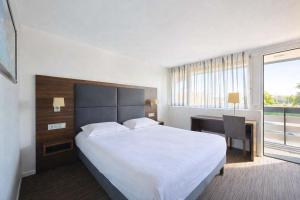 a hotel room with a large bed and a desk at Kyriad Bordeaux - Merignac Aéroport in Mérignac