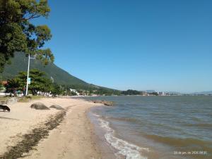 a beach next to the water on a sunny day at Recanto dos Sabiás in Palhoça