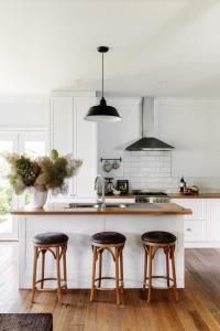 a kitchen with white cabinets and a counter with stools at Corner Cottage Bright in Bright