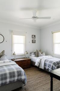 two beds in a white bedroom with two windows at Corner Cottage Bright in Bright
