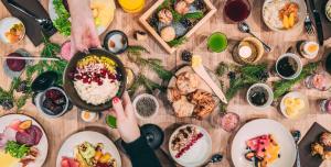 a table full of food and a person holding a pan of food at Lapland Hotels Kuopio in Kuopio