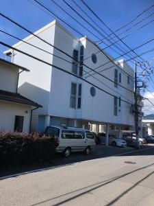 a white building with a van parked in front of it at Maison Lumière in Odawara