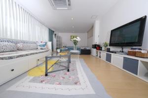 a living room with a couch and a large screen tv at Maison Lumière in Odawara