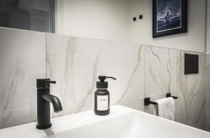 a black bottle of soap on a sink in a bathroom at Ciauru al Sud in Messina +59 photos
