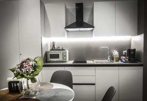 a kitchen with white cabinets and a table with a vase of flowers at Ciauru al Sud in Messina